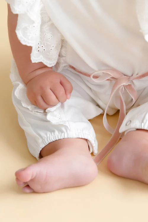 close up of lower half of white baby jumpsuit